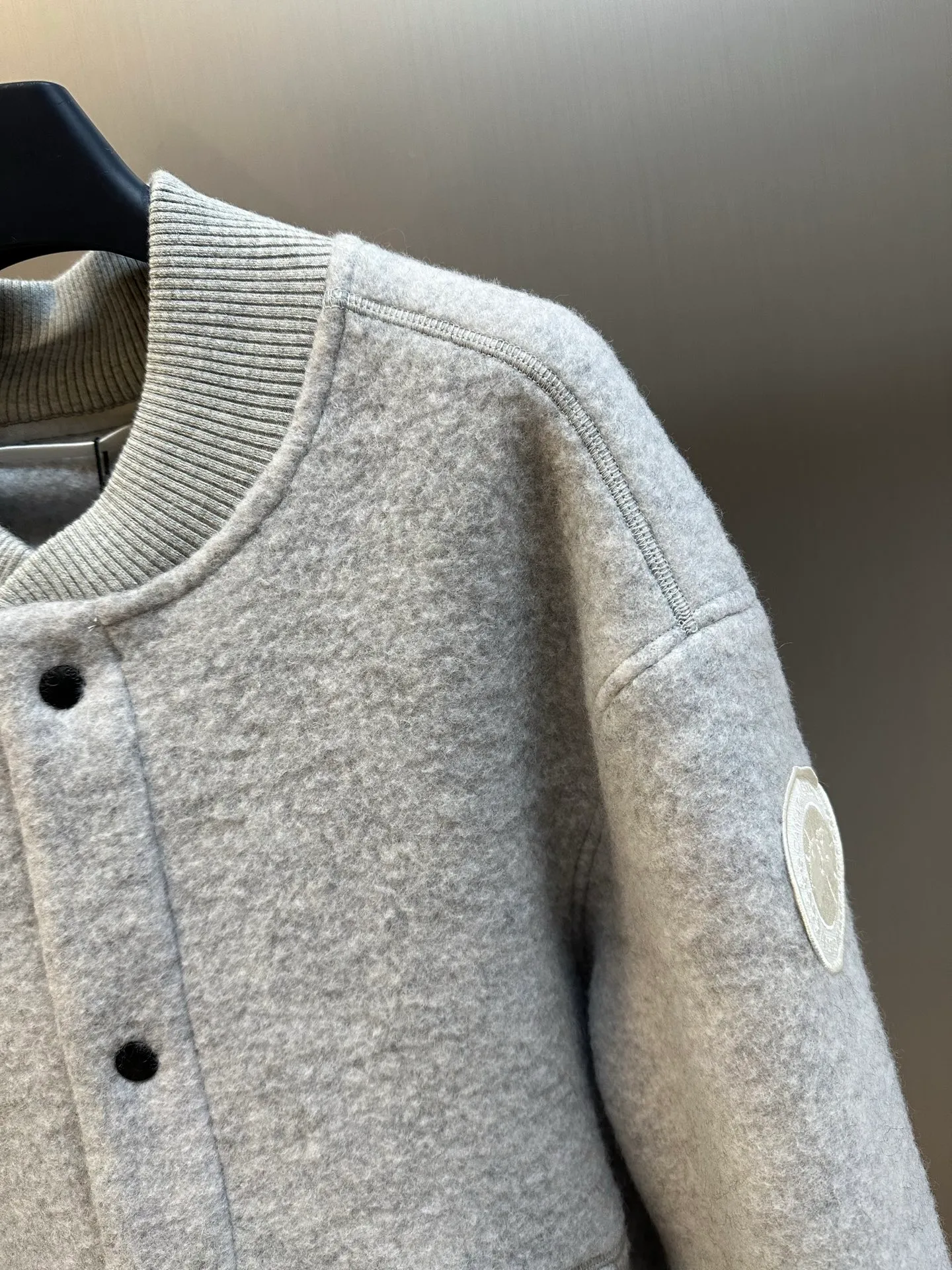 P770 Canada Goose Fleece Badge Button Jacket The main fabric of this jacket is light gray wool blend fabric to improve the fabric's wear resistance, wrinkle resistance and warmth. Wool provides good warmth and a natural feel, while blended fibers enhance the fabric's practicality and durability.  The cutting process needs to ensure that the texture and color of the fabric are evenly distributed, especially with this light gray tone, to avoid chromatic aberrations. The stretchability of wool-blend fabrics needs to be taken into consideration when cutting pieces to ensure dimensional stability of the finished garment.  Use a sewing needle and thread suitable for wool-blend fabrics to avoid damage to the fabric during sewing. The sewing stitches are even and firm to prevent thread stripping.  The temperature needs to be controlled during ironing to avoid high temperature damage to the fabric while keeping the fabric smooth and crisp. The front and back body parts, sleeves and other main parts are stitched with flat seams to ensure a smooth silhouette. Align the fabric texture at the splices to keep the look neat.  The white circular armband on the left arm is an important part of the brand identity and is finely sewn to ensure it is strong and flat.  size：s m l xl